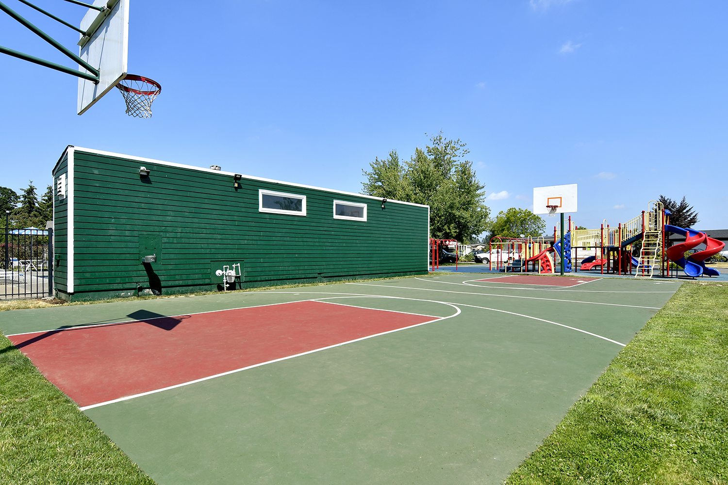 Large outdoor basketball court next to playground.