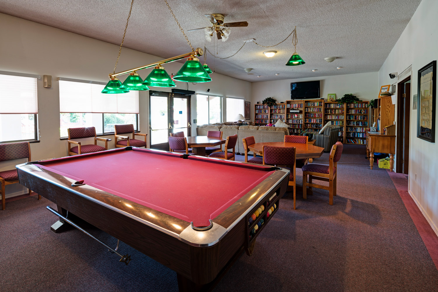 Game room with a pool table and couple tables with chairs to play cards.