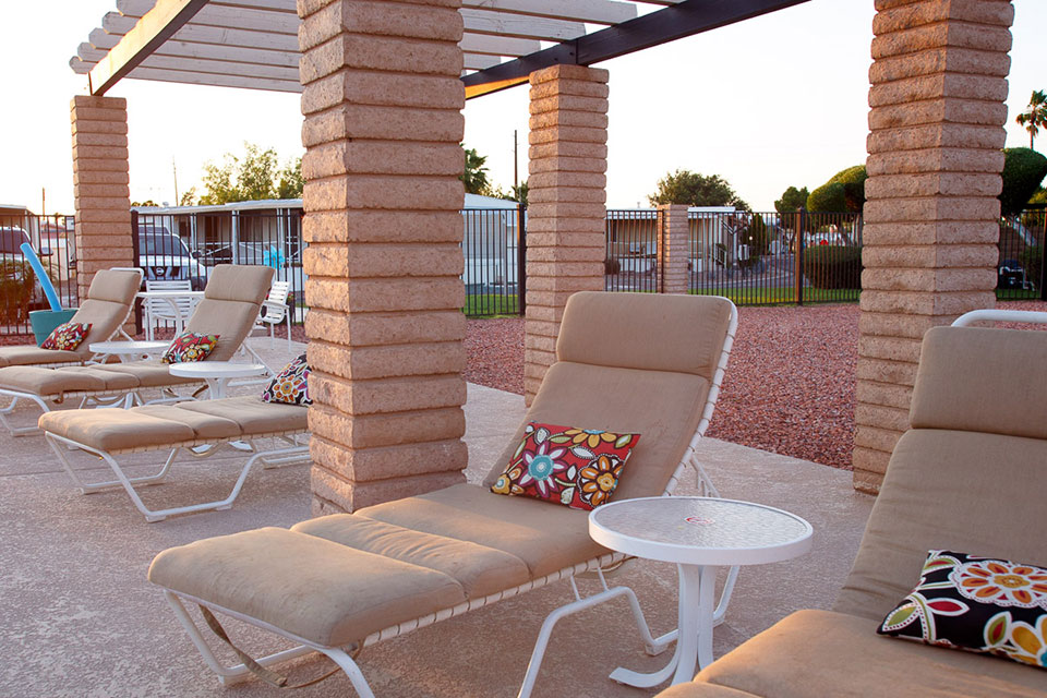 cushioned pool lounge chairs with small pillows and table surround the pool for relaxing.