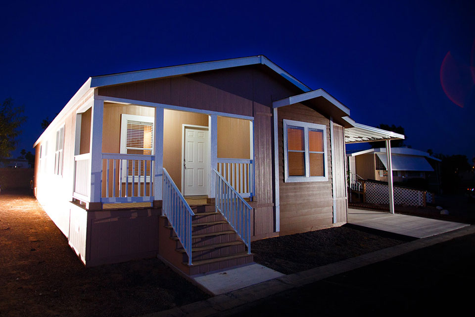 A manufactured home with the porch light on at night