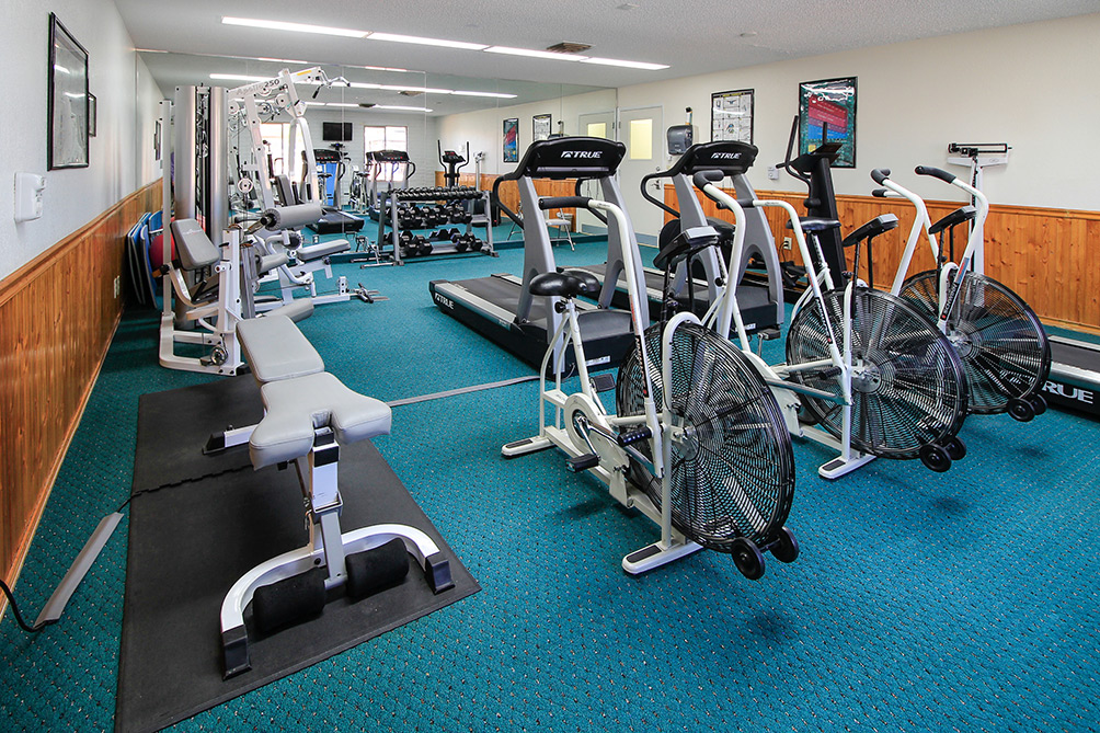 Well equipped fitness room with free weights, treadmills, bicycles, bench, yoga ball and mats and scale