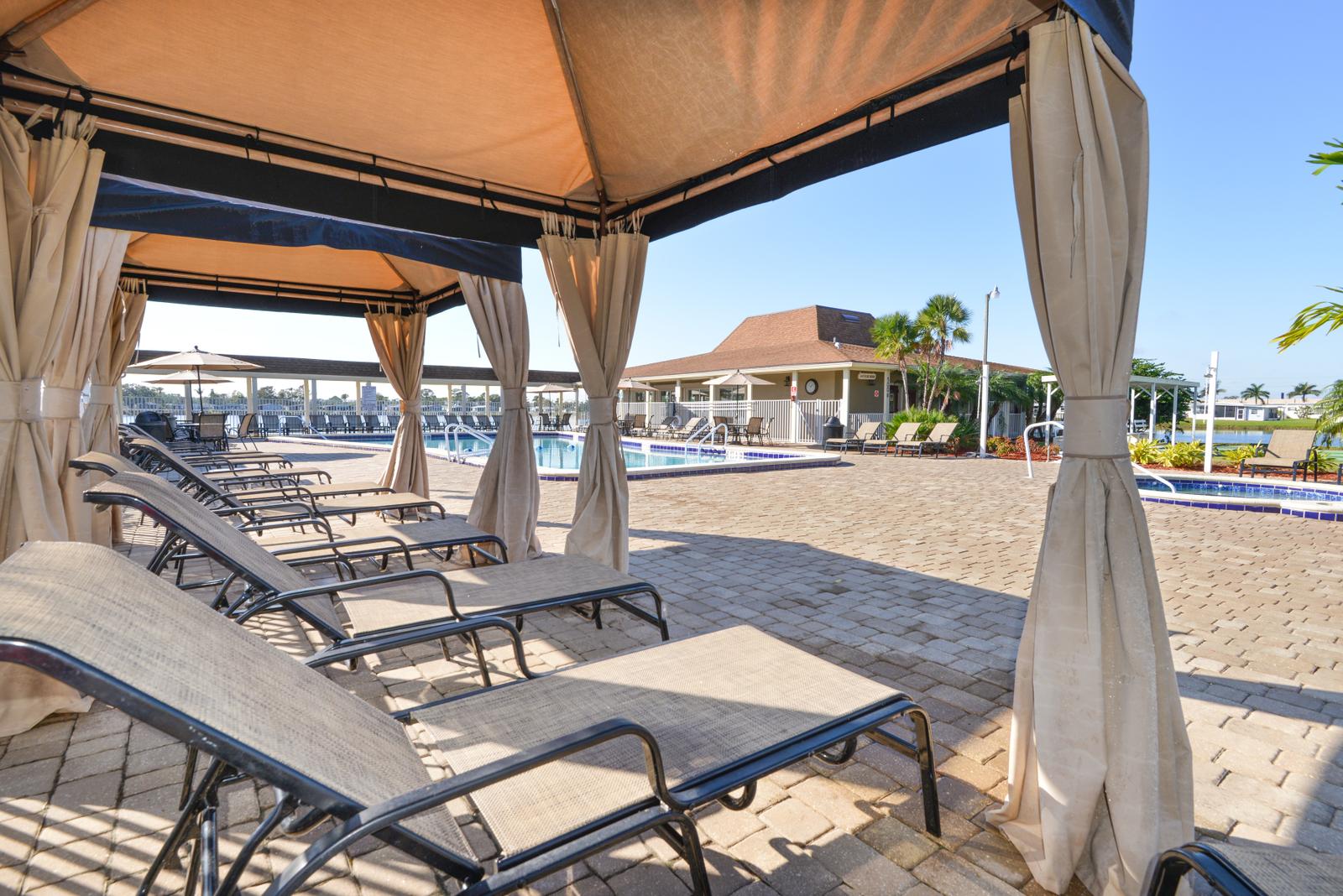 Large cabanas with lounge chairs offer shad in pool area.