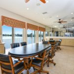 Enclosed meeting room as part of the clubhouse. Two conference tables with chairs overlook the lake with wide open windows. Tan cabinets