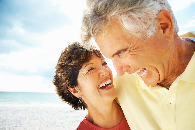 Portrait of a happy loving mature man and woman laughing on beach.