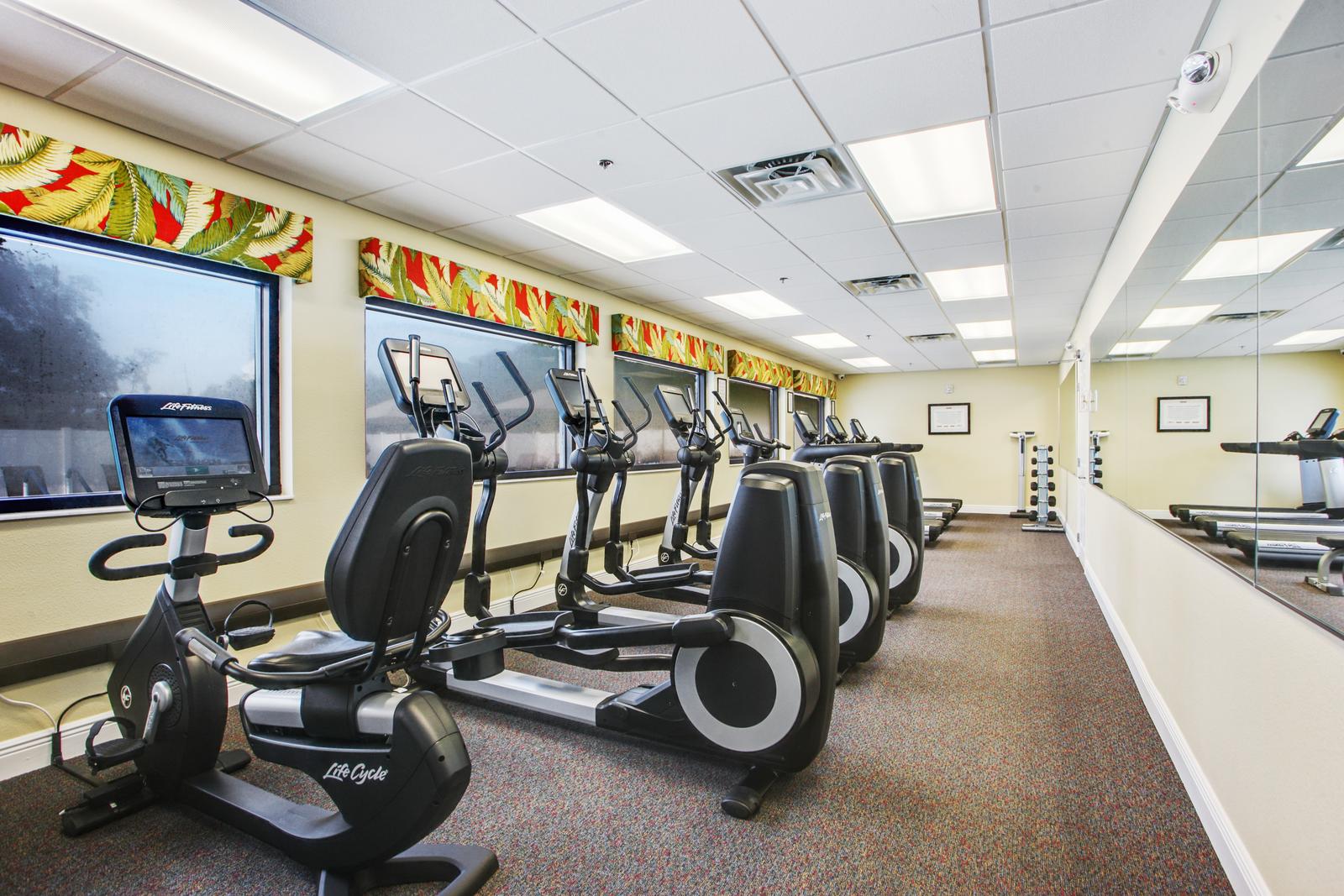 Long exercise room with stationary bikes, elliptical machines, treadmills and free weights.