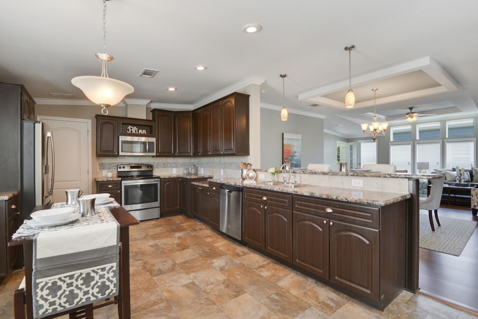 Beautiful new kitchen with dark wood cabinets and granite countertops. Stainless steel appliances. Recessed lighting and tile flooring. Opens up into living room.