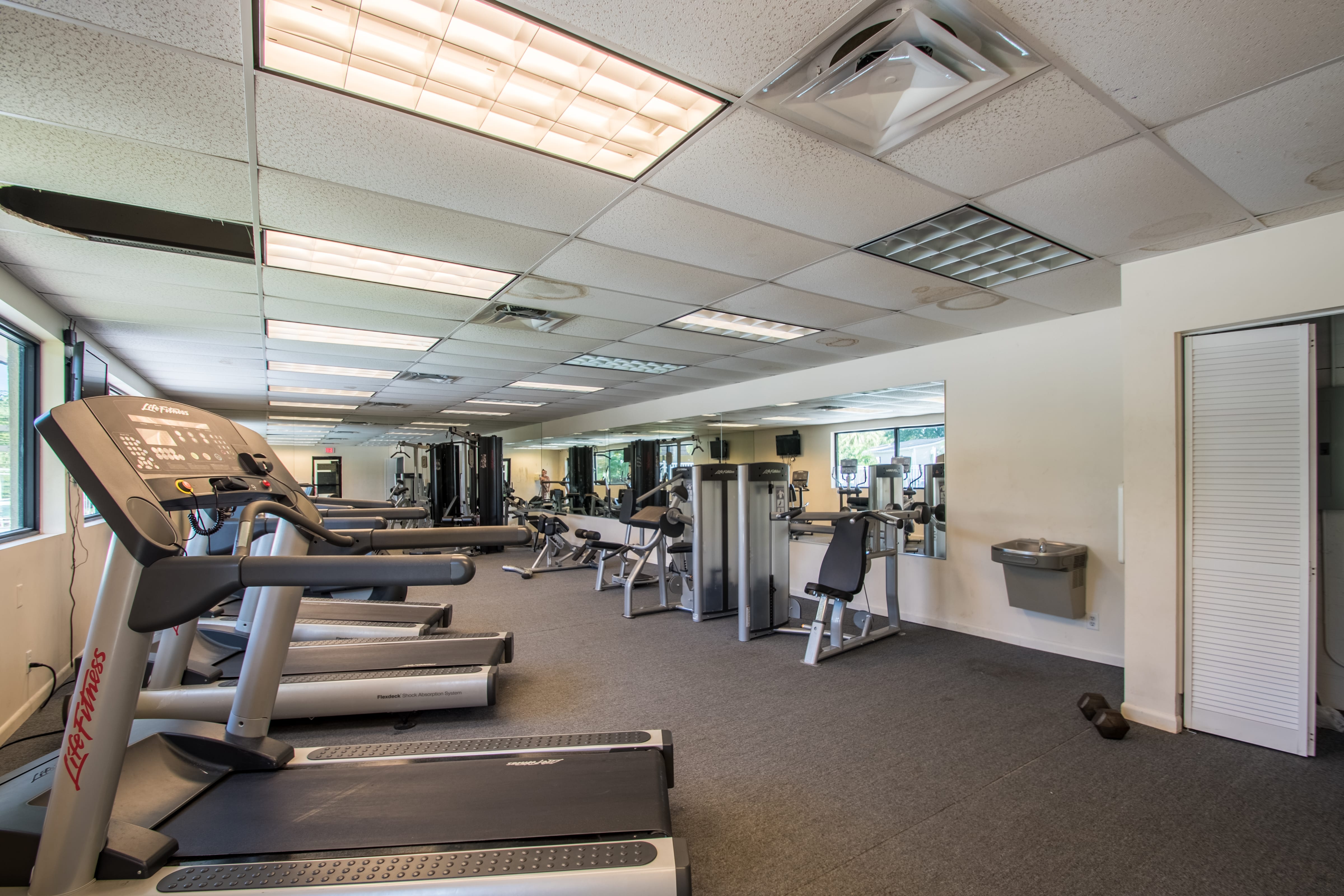 Fitness center in the community equipped with treadmills, weight machines and water fountain.