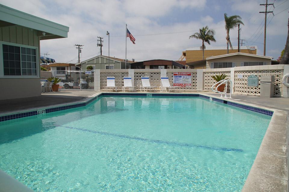 Full-size outdoor community pool enclosed by metal and beige concrete gates.