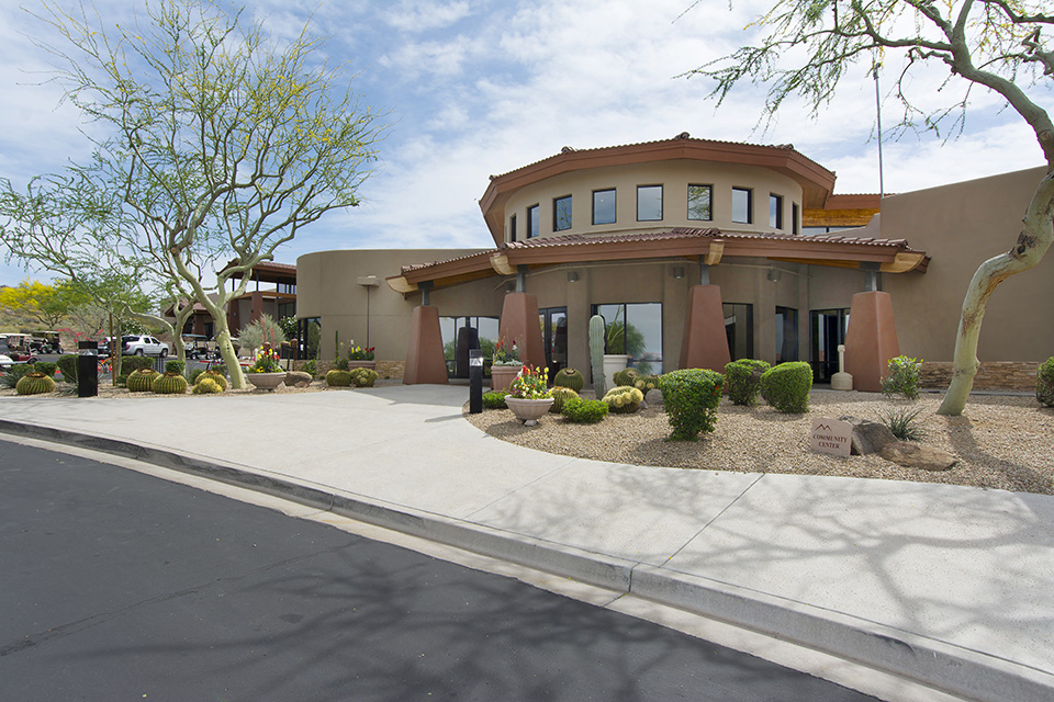 Montesa at Gold Canyon has a dome shaped community center with trees, cactus, and shrubbery landscaped around it outside