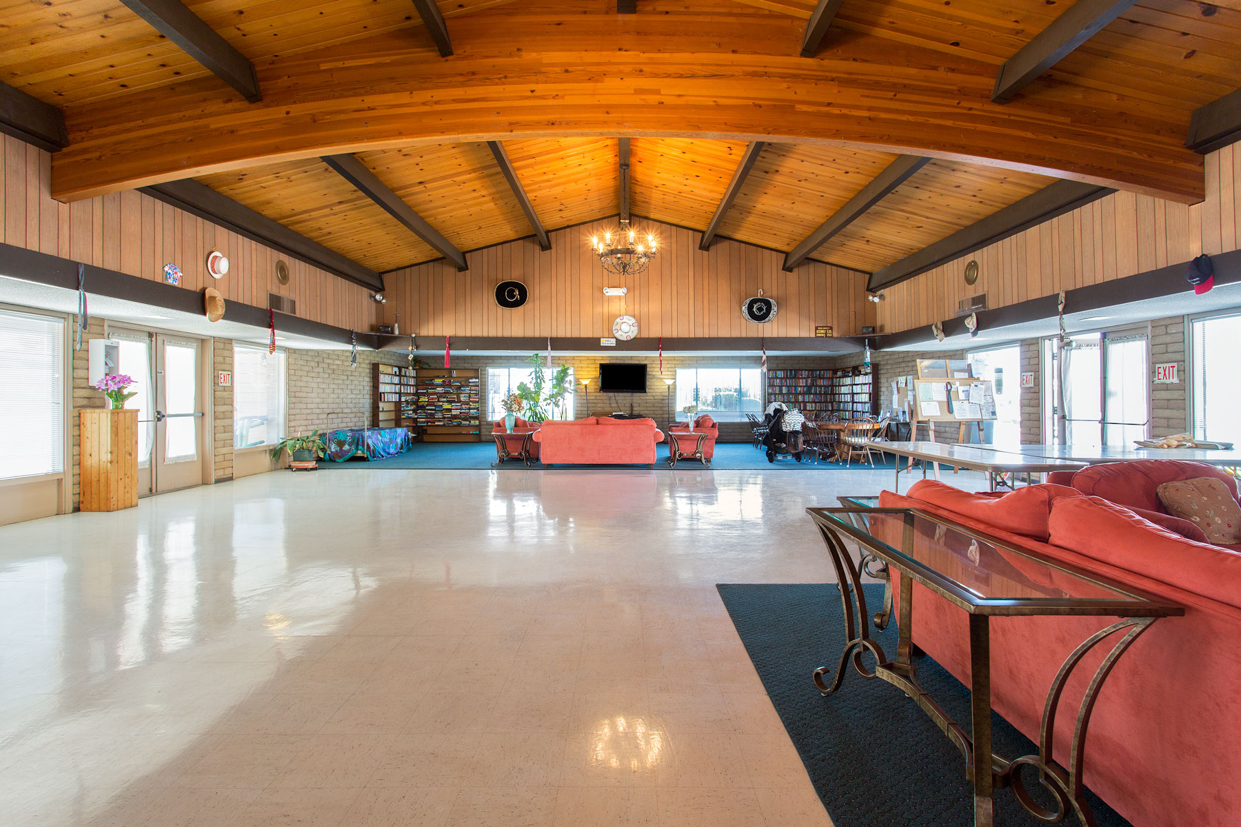 Large, open community center with high, light-wood, vaulted ceilings. Space for residents to lounge on the salmon pink couches or read a book from the novels provided.
