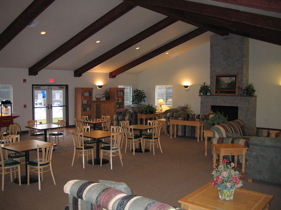 Inside community center with tables and chairs. Vaulted ceiling.