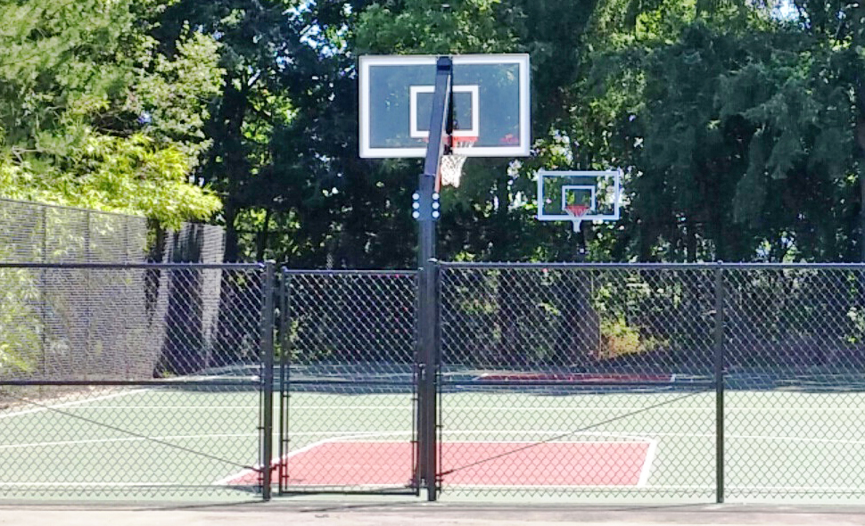 New outdoor basketball court with shaded trees in the background.