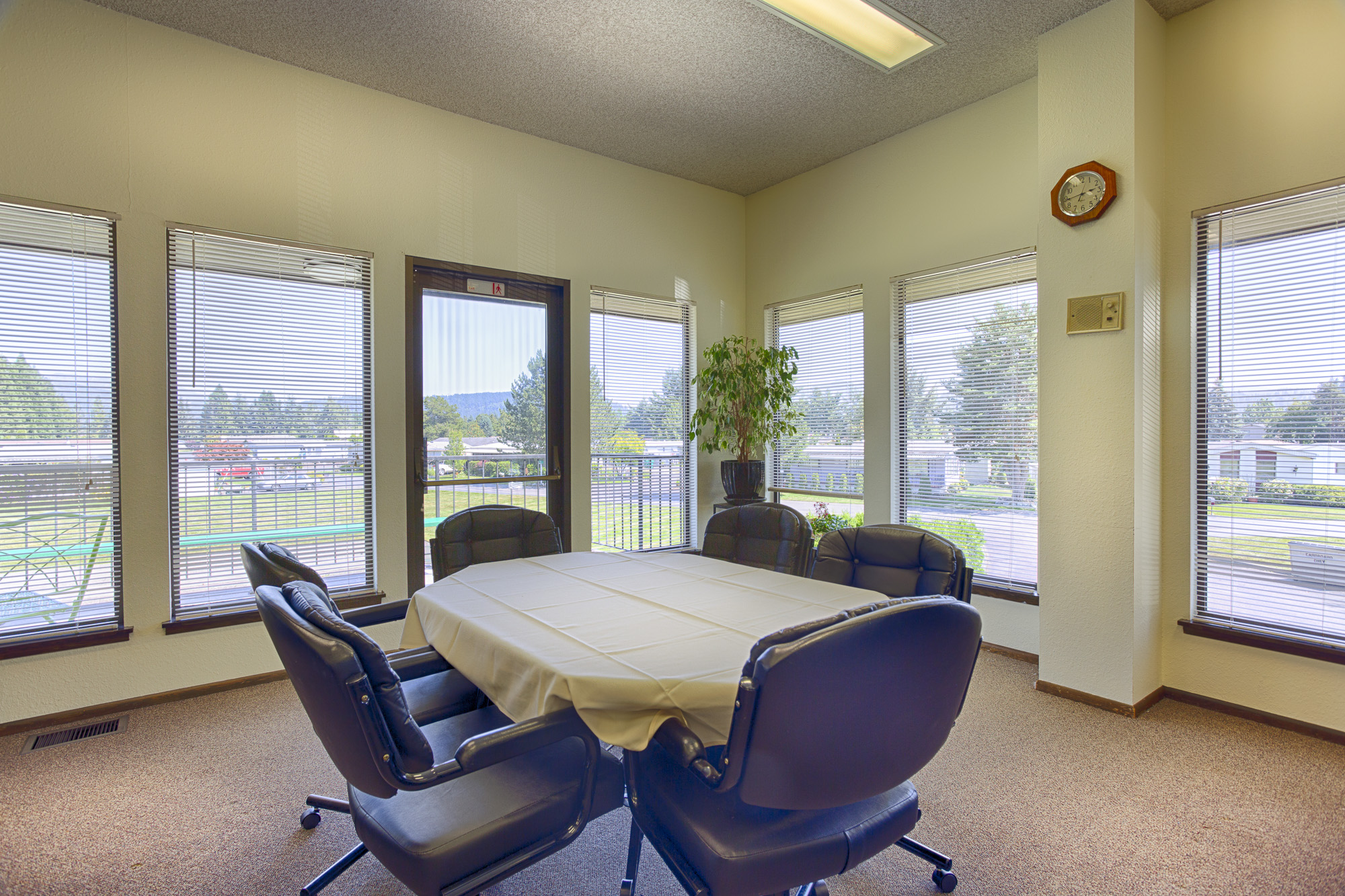 Oval table within the community center that fits six seats comfortably. Cushioned seats surround the table and have a beautiful view of the outdoors through the windows along the walls.