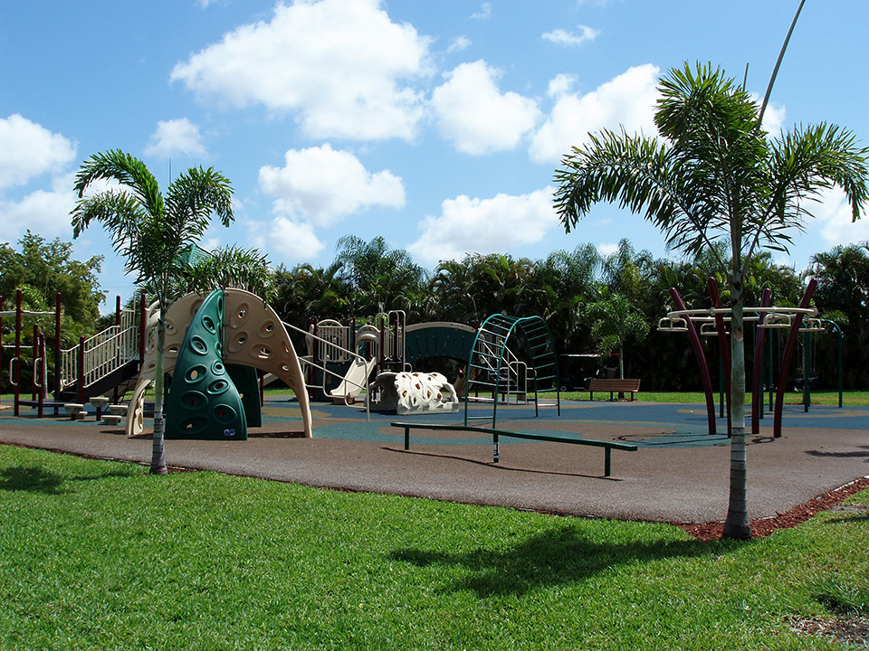 A big playground for children. There are monkey bars, slides, balance bar and swings. Bench seating is all around the perimeter of the playground.
