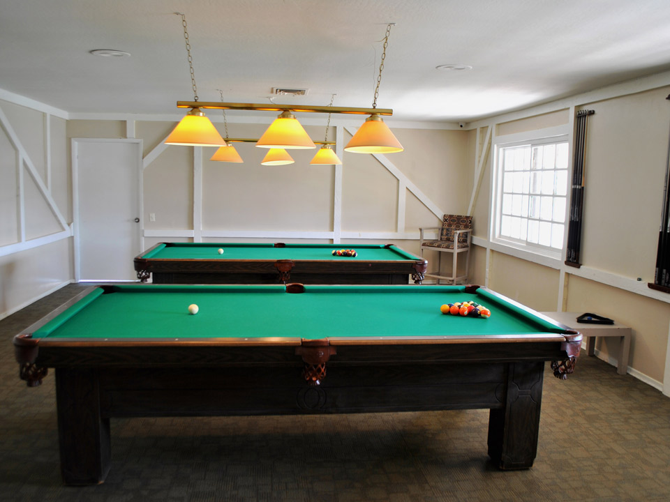 A billiard room with two pool tables.