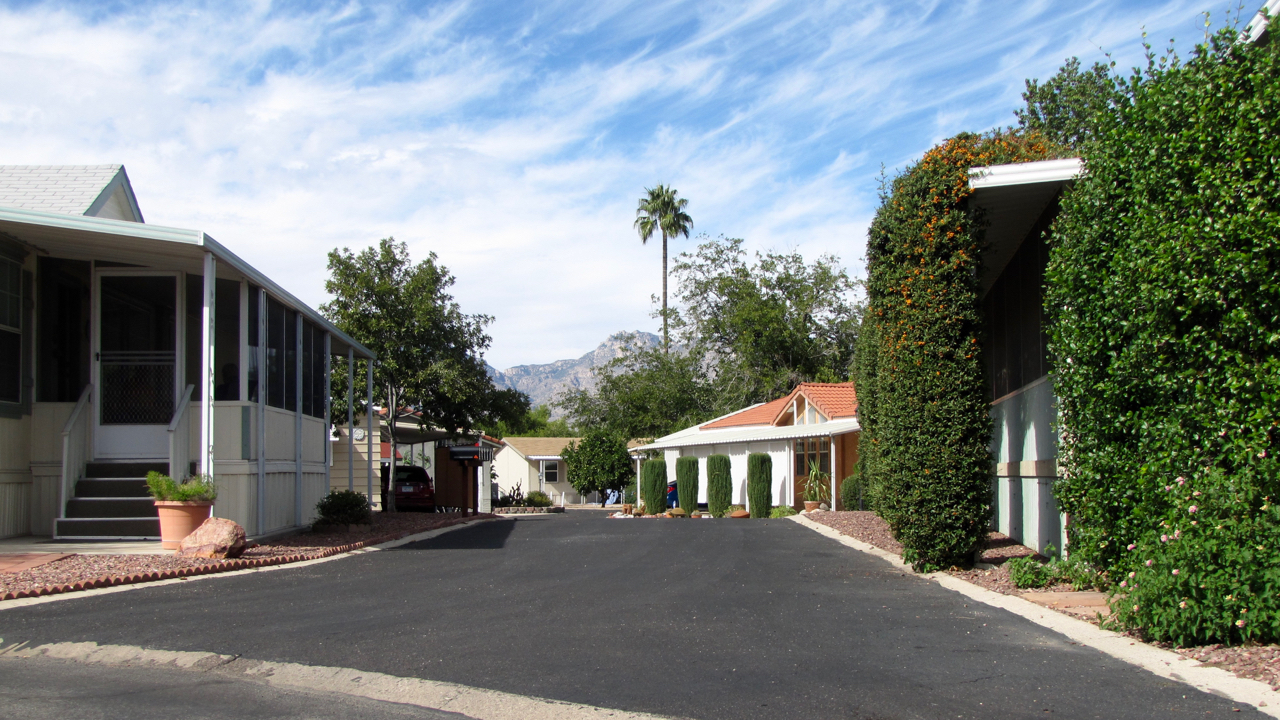 A quiet, peaceful, clean neighborhood with shade trees and mountains as the background.