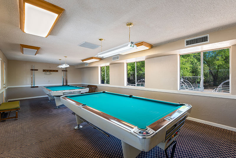 Billiards room with access to two billiards tables. Neutral colors throughout and windows with a view of the outdoors.